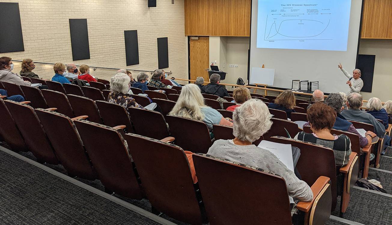 People listening to person giving presentation in auditorium