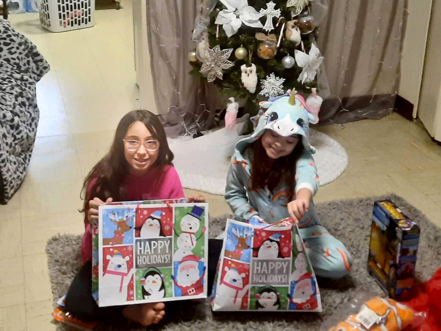 Children smiling, holding the gifts they received from Kidz N Coaches.