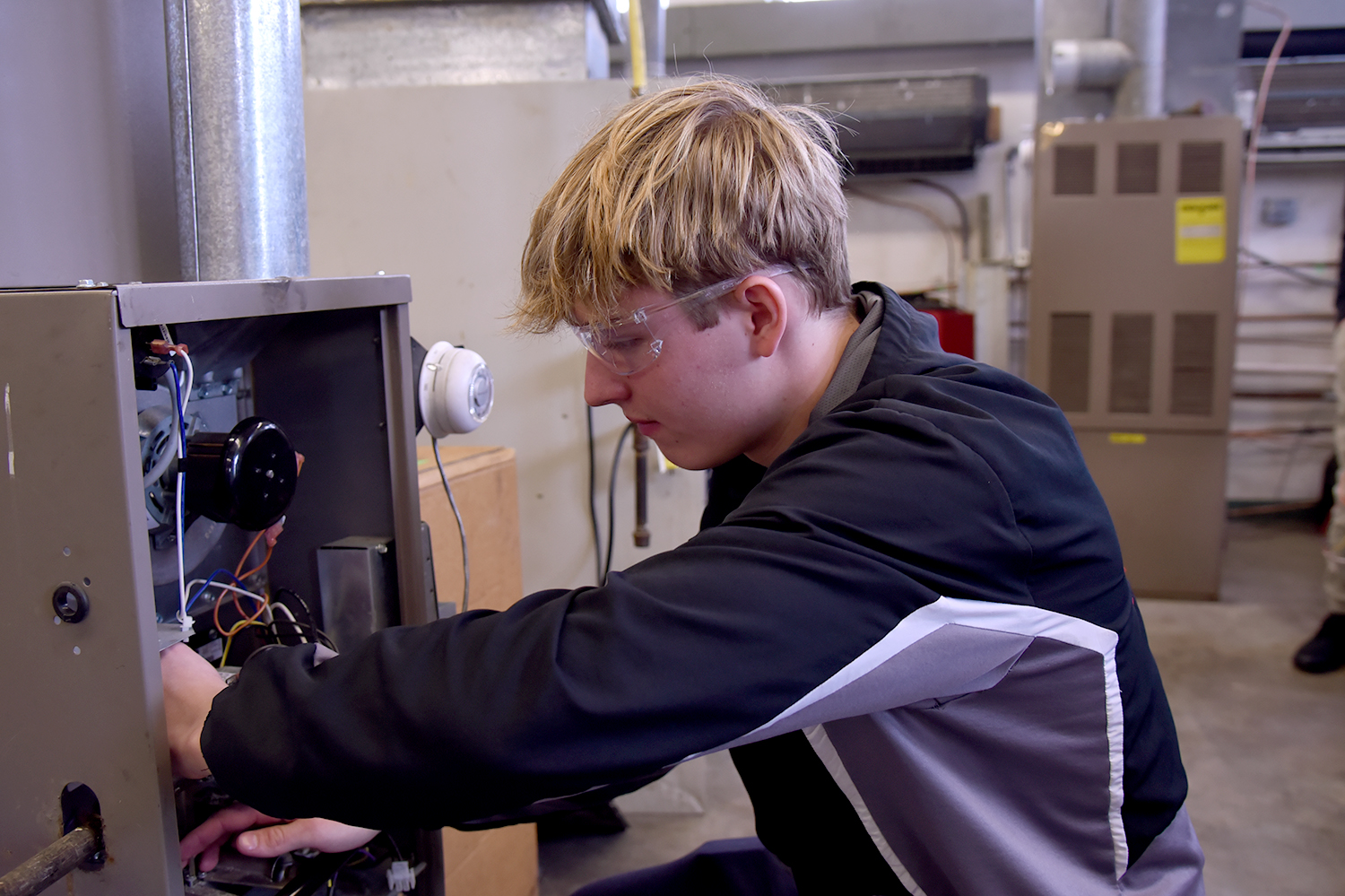 Student fixing wiring on a heating unit.