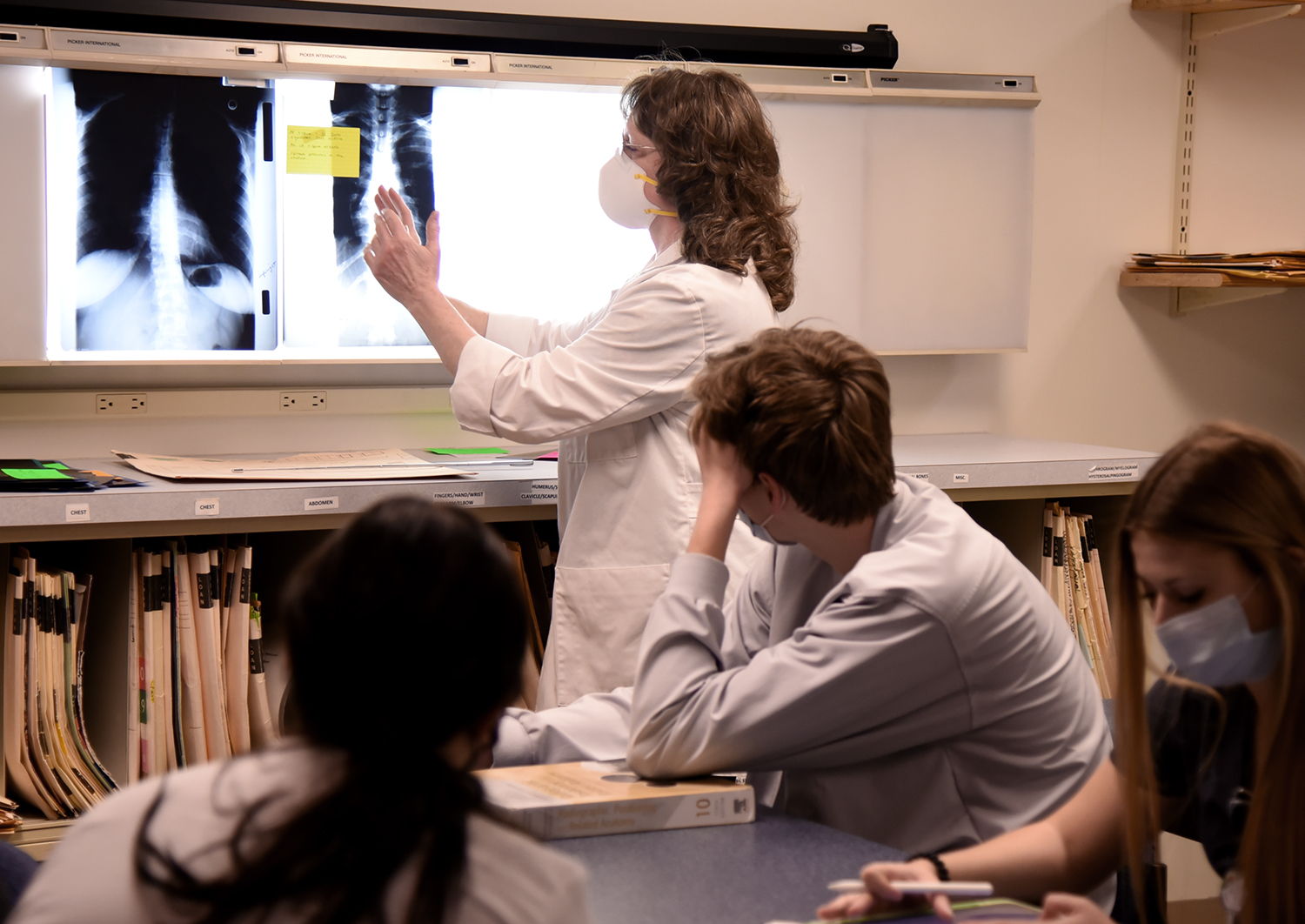 A faculty member looking at an X-Ray in a radiologic technology class