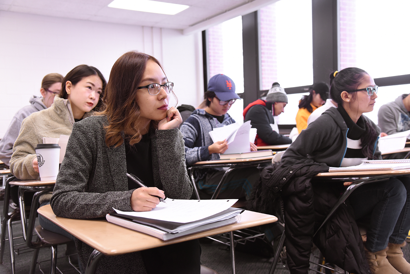 Students sitting in classroom, listening, taking notes