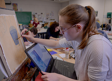 Image of art student painting in class