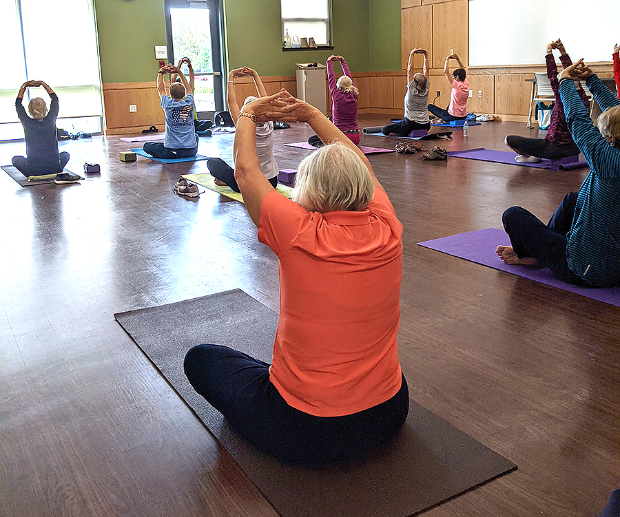 Yoga class, people stretching on mats on the floor indoors