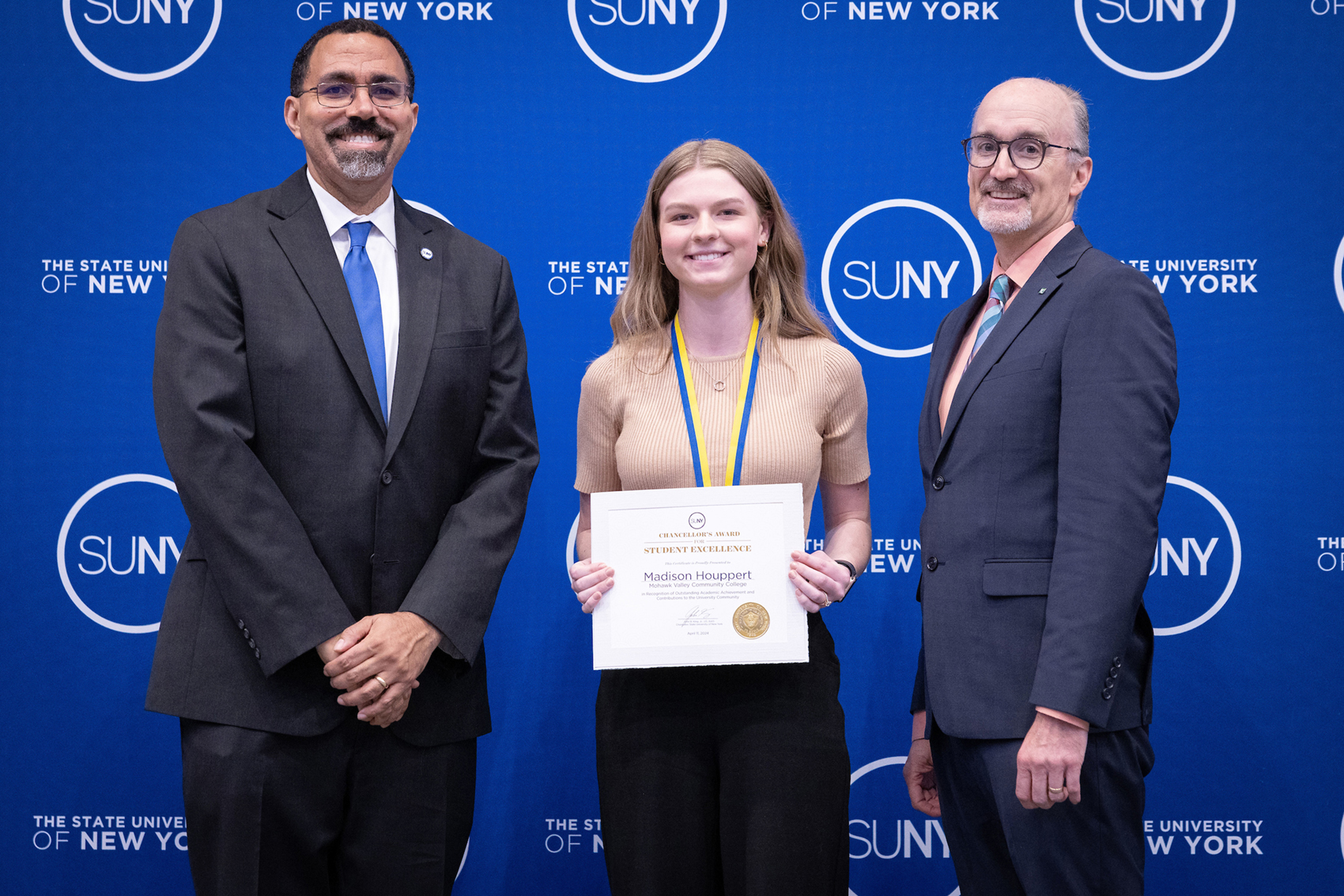 Three people standing in front of blue SUNY backdrop