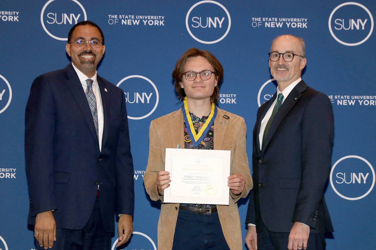 Image of three people standing in front of blue suny background; SUNY Chancellor John King, MVCC student Aidan Ferguson holding certificate, MVCC President Randall VanWagoner