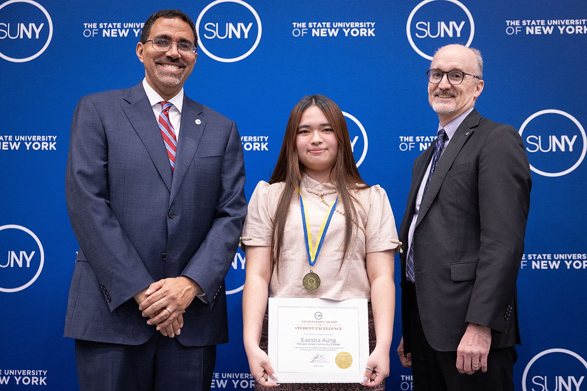 Three people standing in front of blue background with SUNY logo