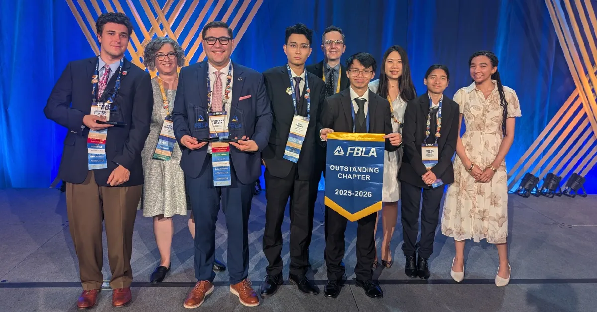 Nine people standing on a stage, one is holding a sign that says "FBLA Outstanding Chapter 2025-2026"