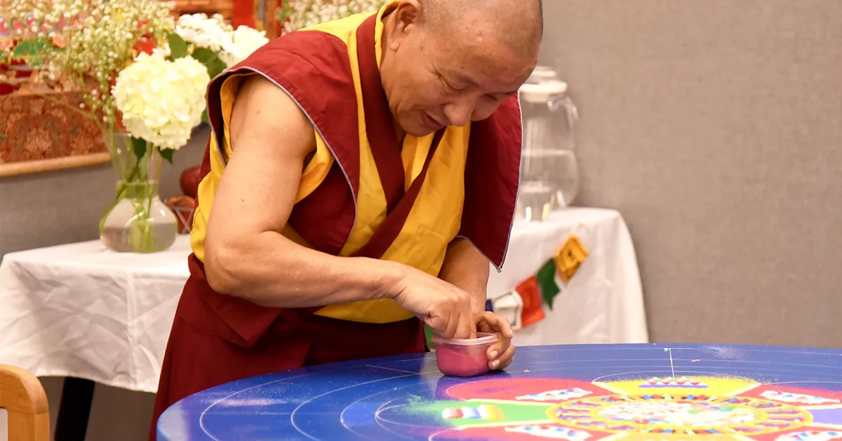 Mandala of Compassion Buddhist monk using colored sand to create a mandala on a table