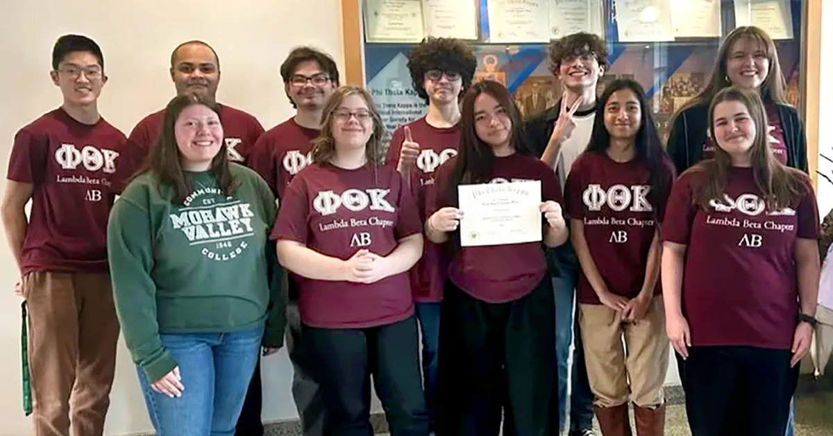 MVCC PTK Regional Awards MVCC PTK students standing together in matching shirts, the chapter president is in the middle of the group, holding an award certificate