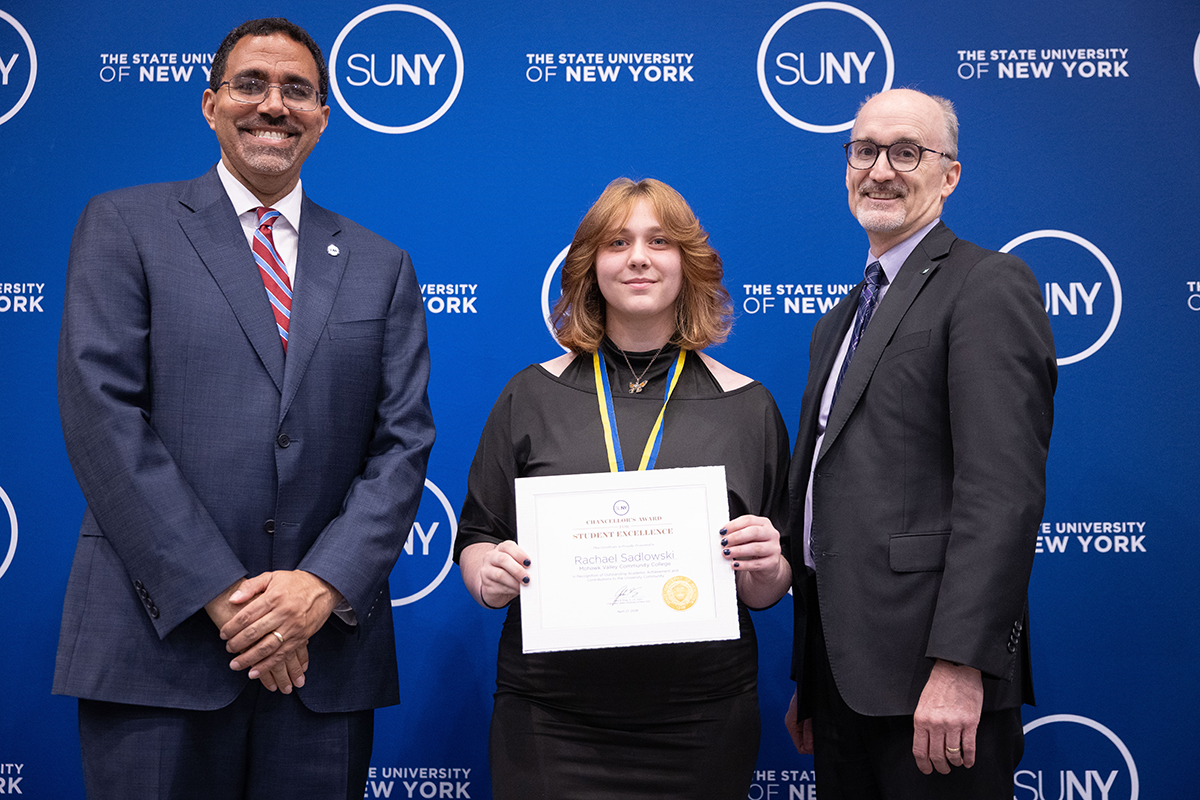 Three people standing in front of blue background with SUNY logo