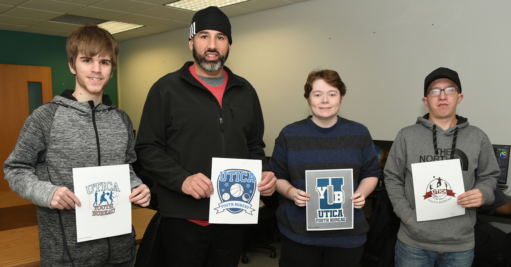 MVCC Graphic Design students’ logos were chosen by the City of Utica Youth Bureau. From left: MVCC student Adam Naresky; Utica Youth Bureau Assistant Director Chet LoConti, who is holding the logo designed by MVCC student Kendra Barajas; and MVCC students Taylor Smith and Chad Garnsen.