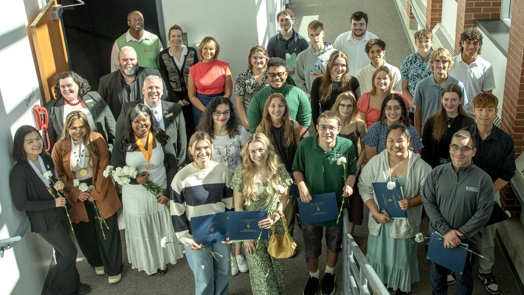 Group of MVCC students, faculty and staff standing on stairs, looking up, smiling