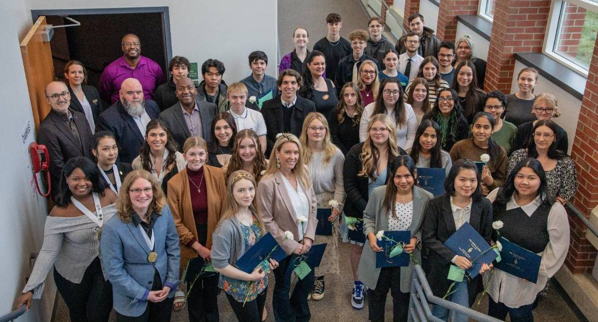 Group of MVCC students, faculty and staff standing on stairs, looking up, smiling