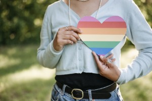 person holding a rainbow hear over their chest