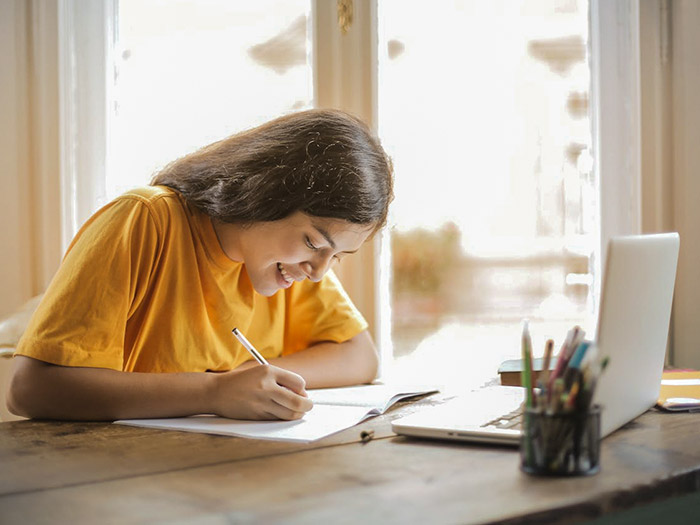 image of student sitting and writing on paper